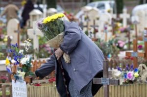 Una persona depone fiori su una tomba al cimitero Laurentino a Roma in occasione della ricorrenza di Ognissanti, 1 novembre 2012. ANSA/CLAUDIO PERI